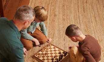 senior man playing chess with grandsons