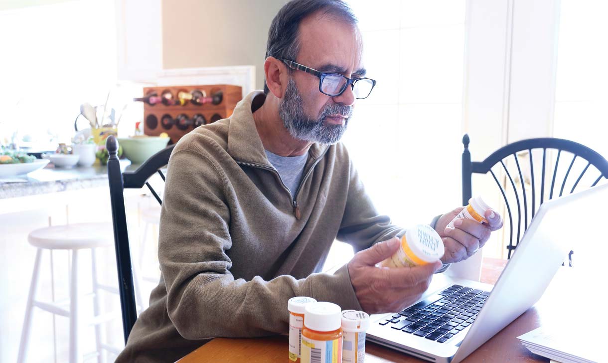 Senior man with laptop and medication