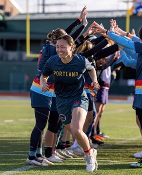 woman professional frisbee player running through teams arms