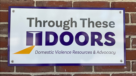 Through the doors logo on brick wall