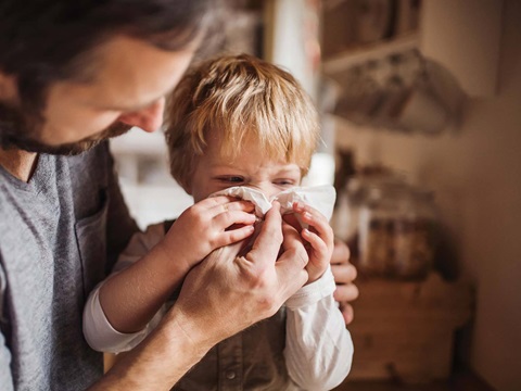 Parent helping child wipe nose