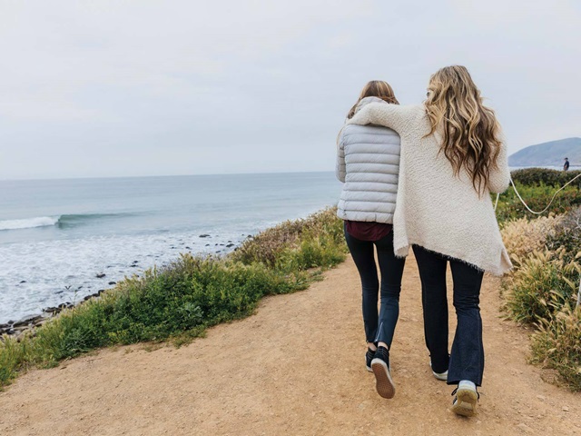 mom and daughter walking along ocean