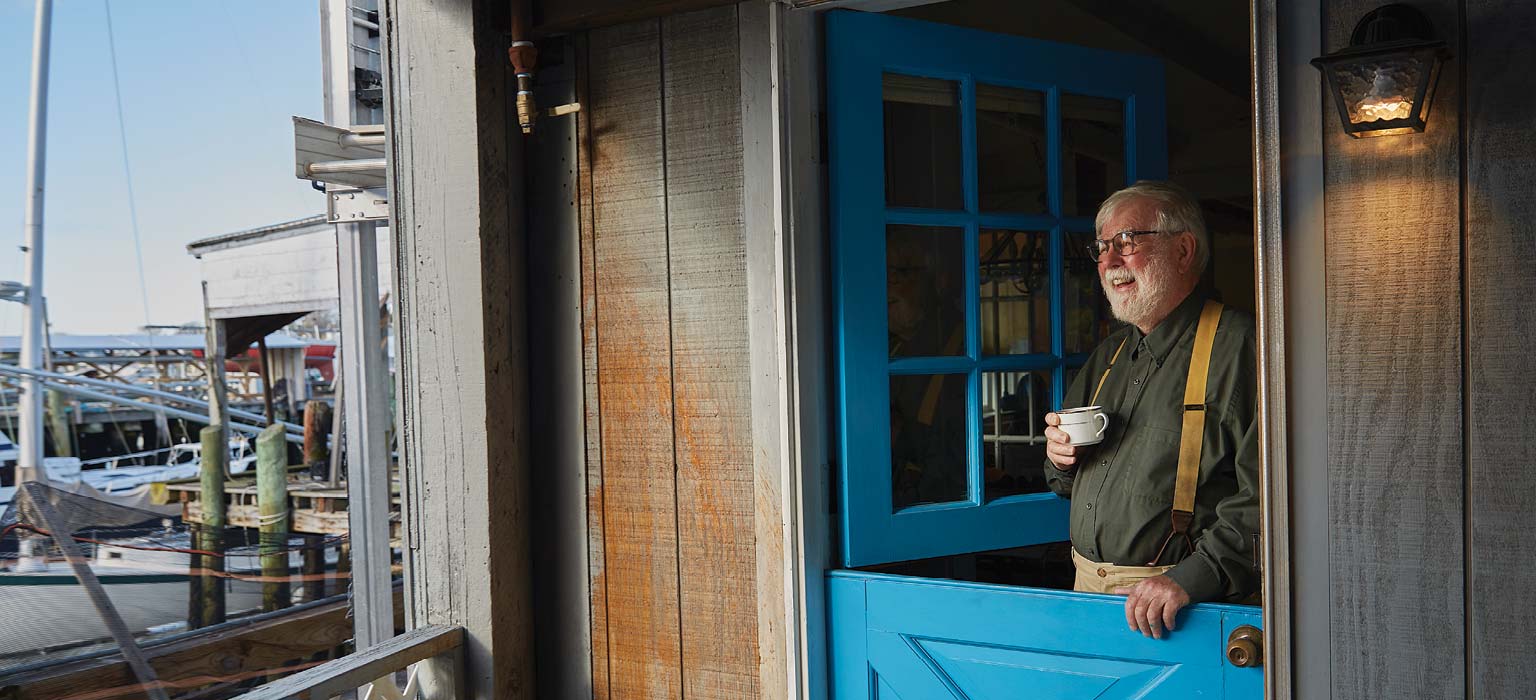 Man holding a coffee cup by a marina
