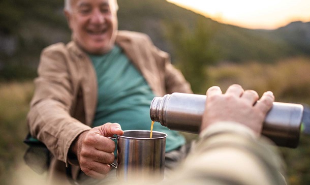 Medicare member outdoors sipping hot coffee