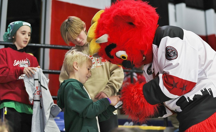 Utica Comets mascot with a child