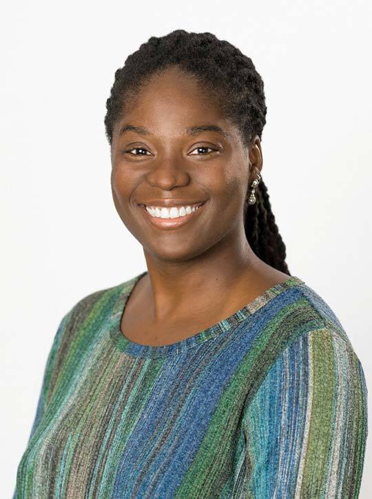 Dr. Miriam Uduebor smiling in a professional headshot, wearing a multicolored striped sweater against a plain white background.