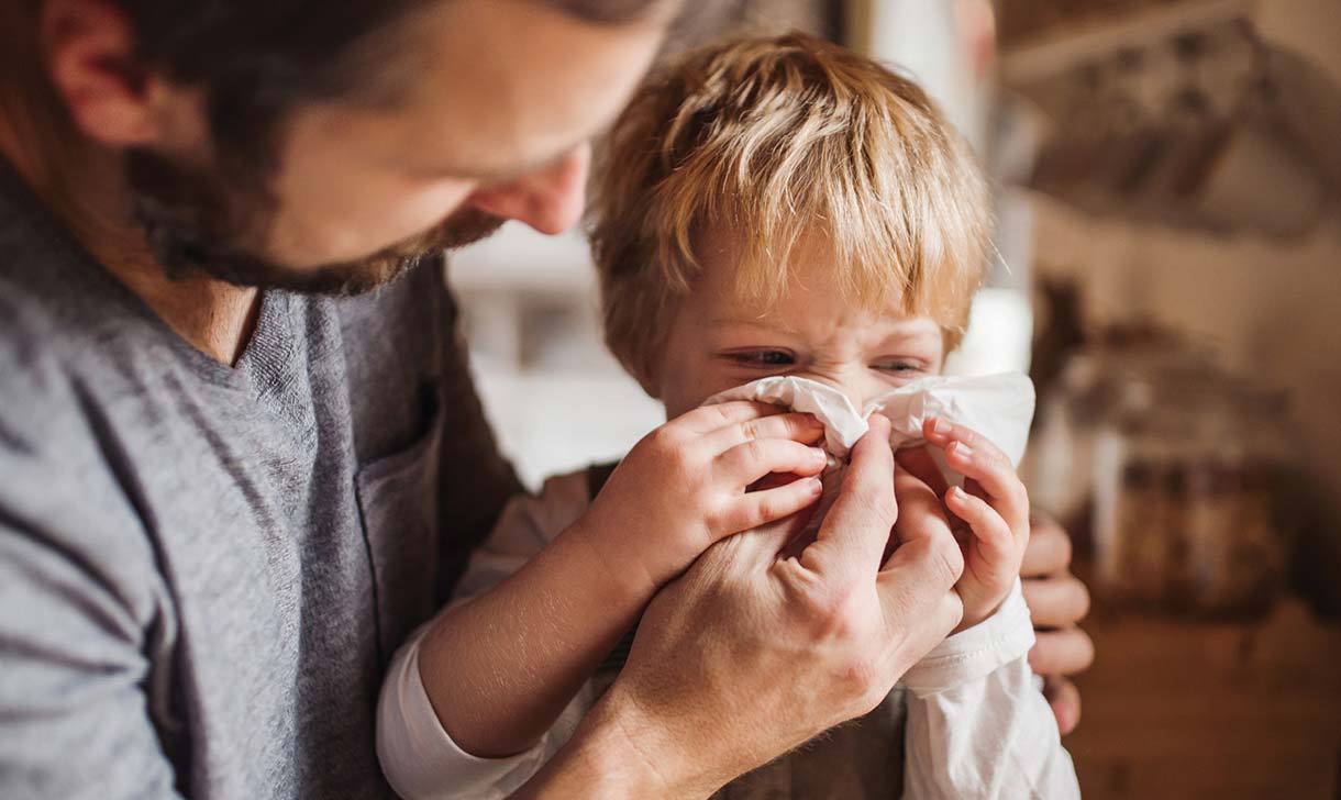 man wiping child's nose