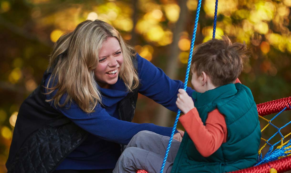 mom pushing son on swing
