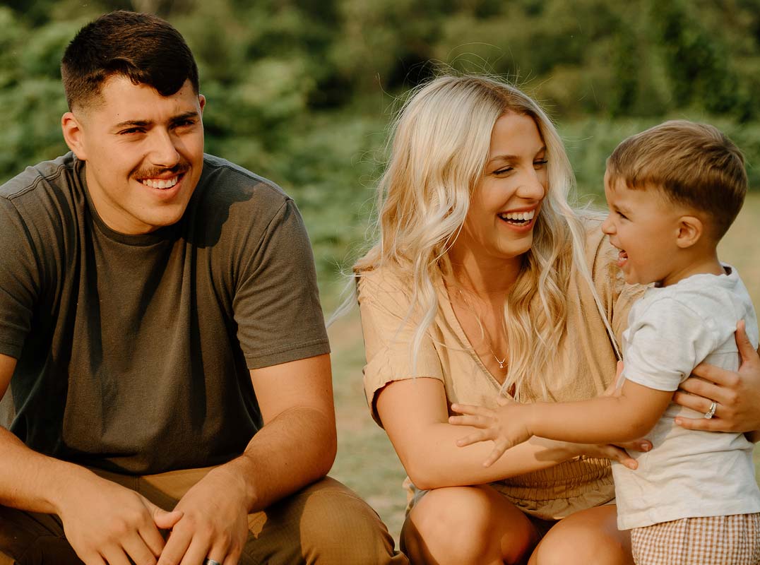 young family playing with son outside