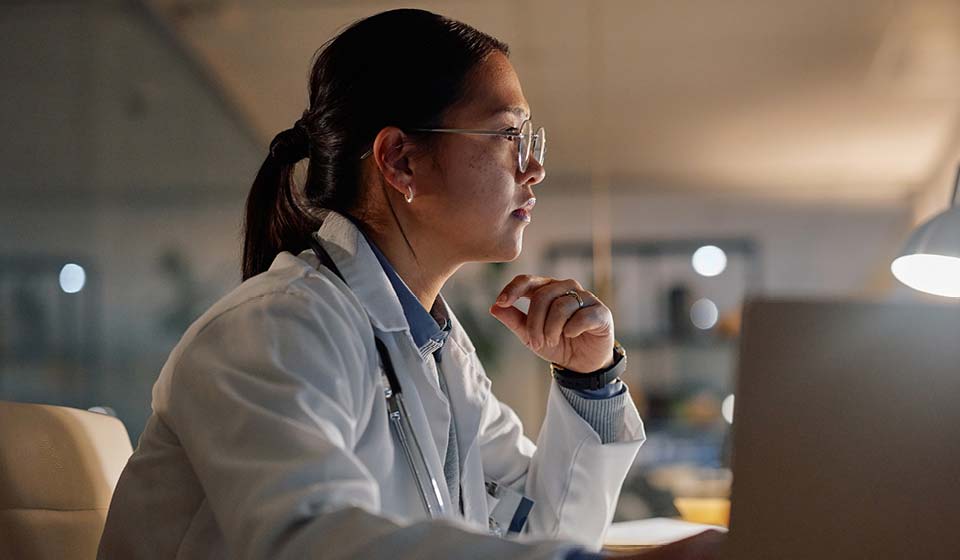 Doctor working late at a laptop under warm light.