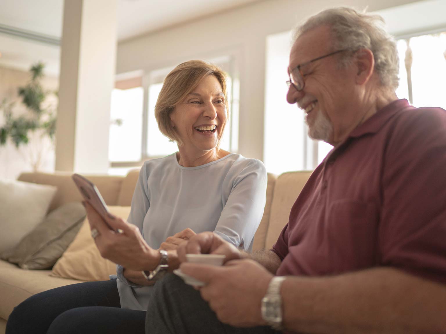 Senior couple smiling while looking at a tablet together.