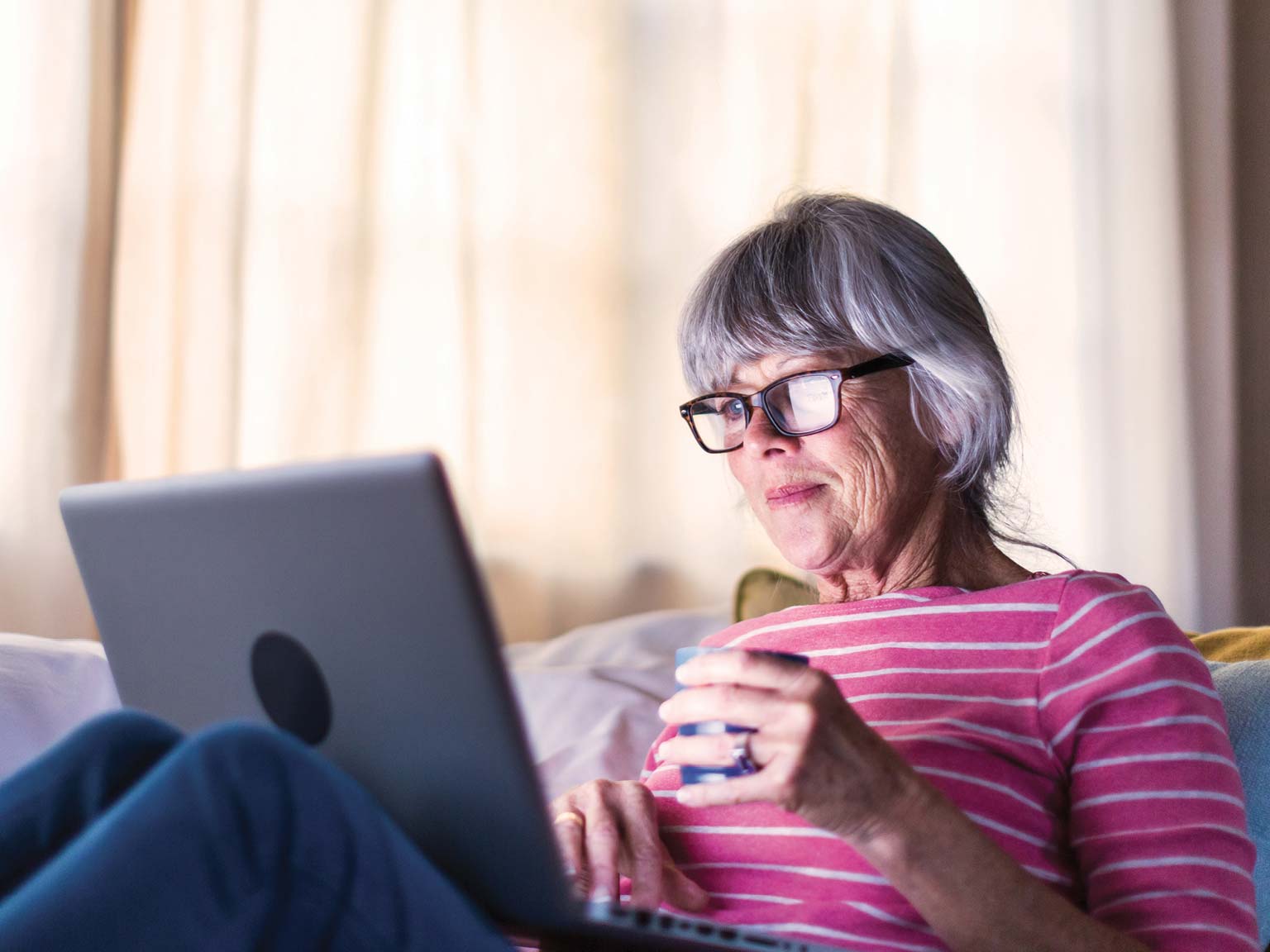 Senior woman using a laptop while sitting at home.