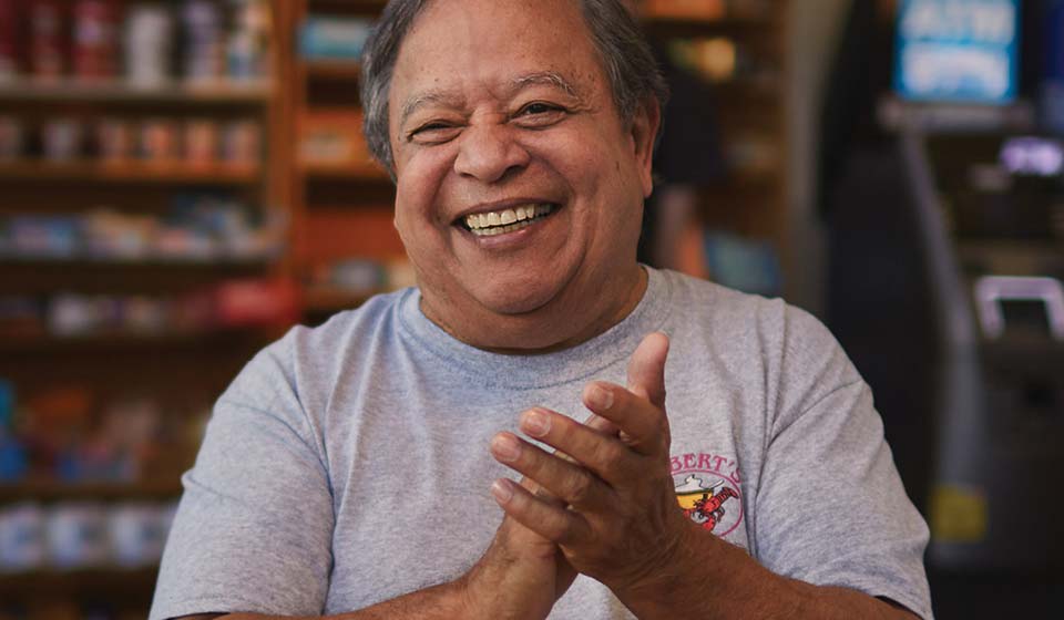 Man smiling and clapping hands in a small shop.