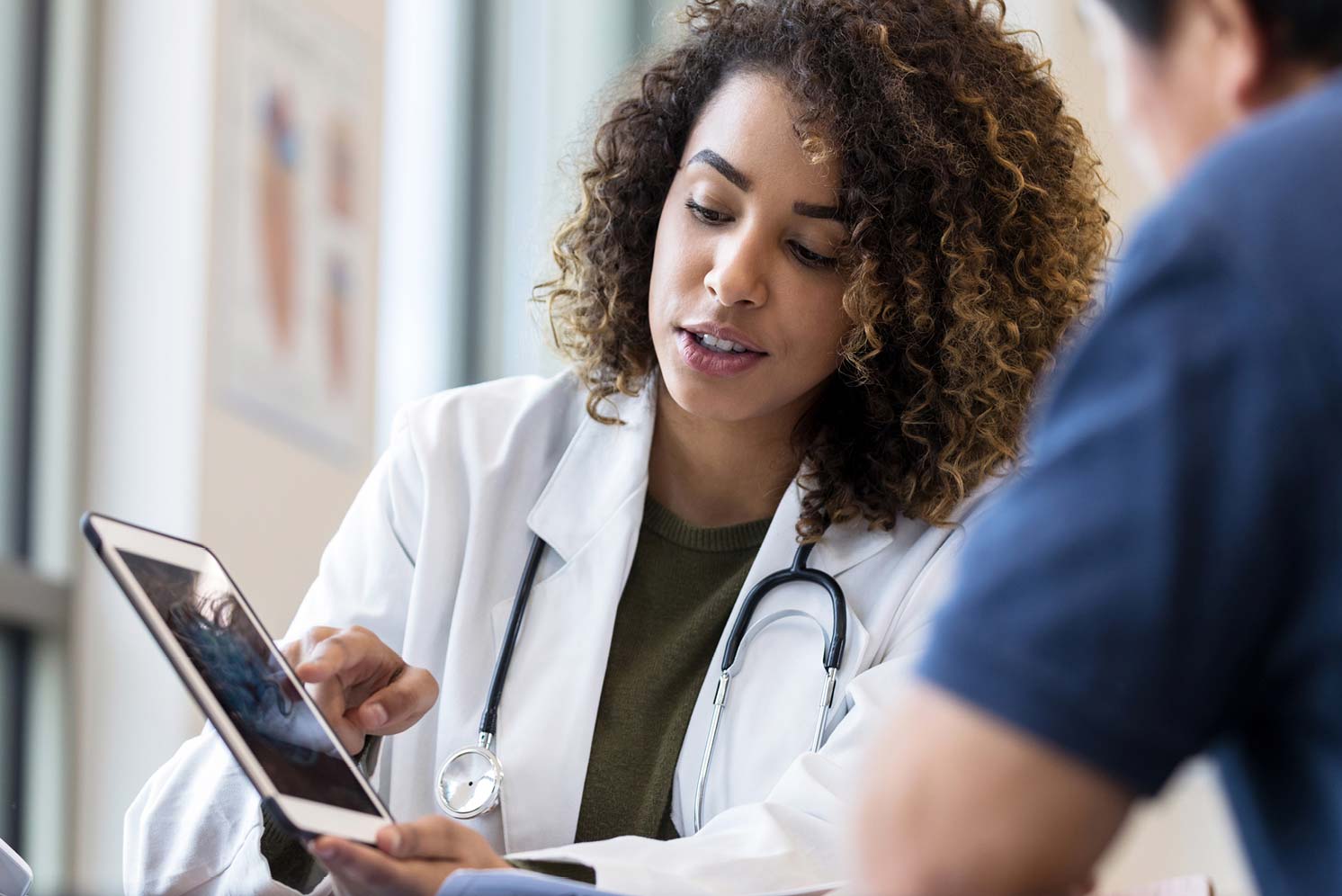 Female doctor reviewing information on a tablet with a patient