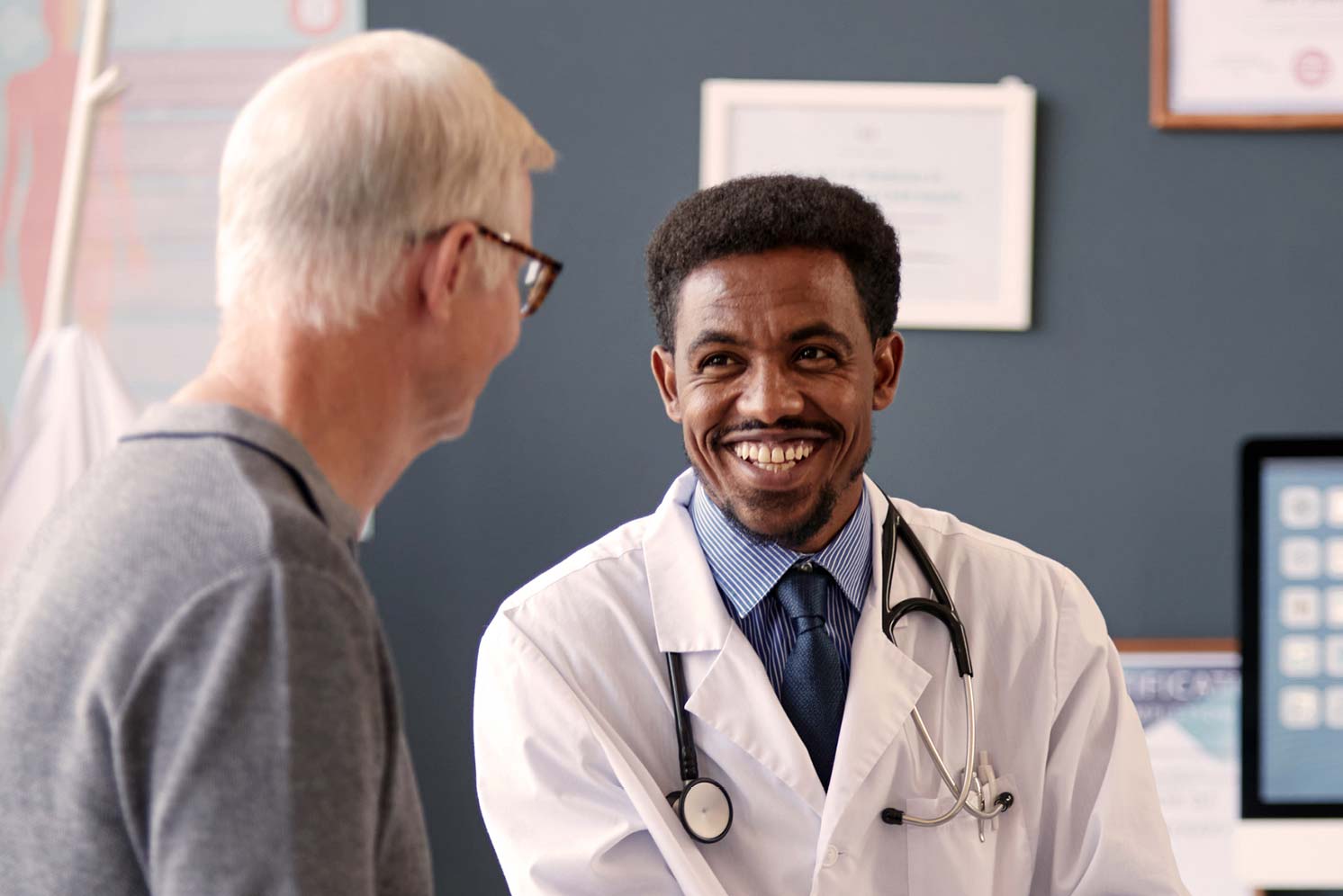 Doctor smiling while speaking with an older male patient