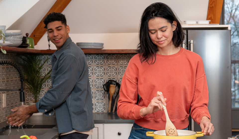 Smiling couple cooking together in a cozy kitchen.
