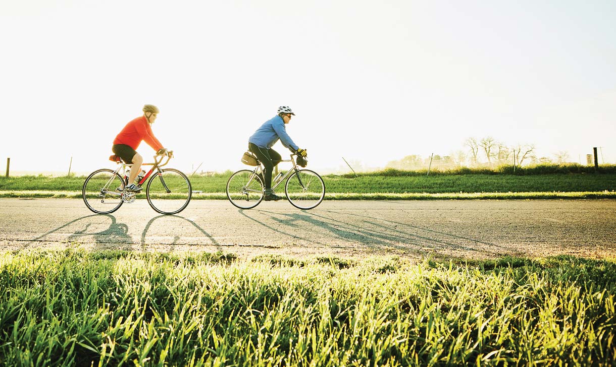 Two people riding bicycles along a rural road.