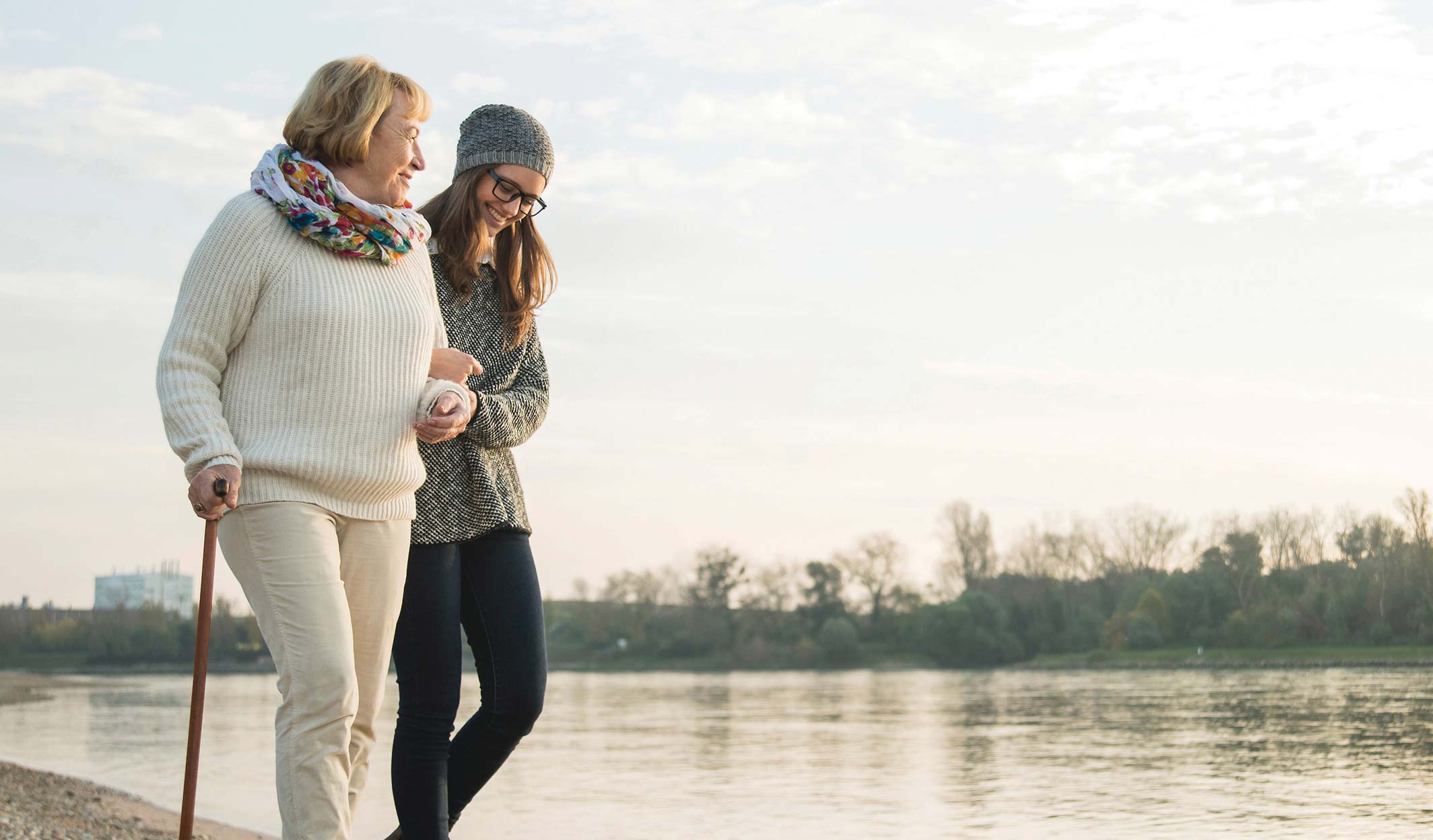 Mother and daughter walking together along a river.