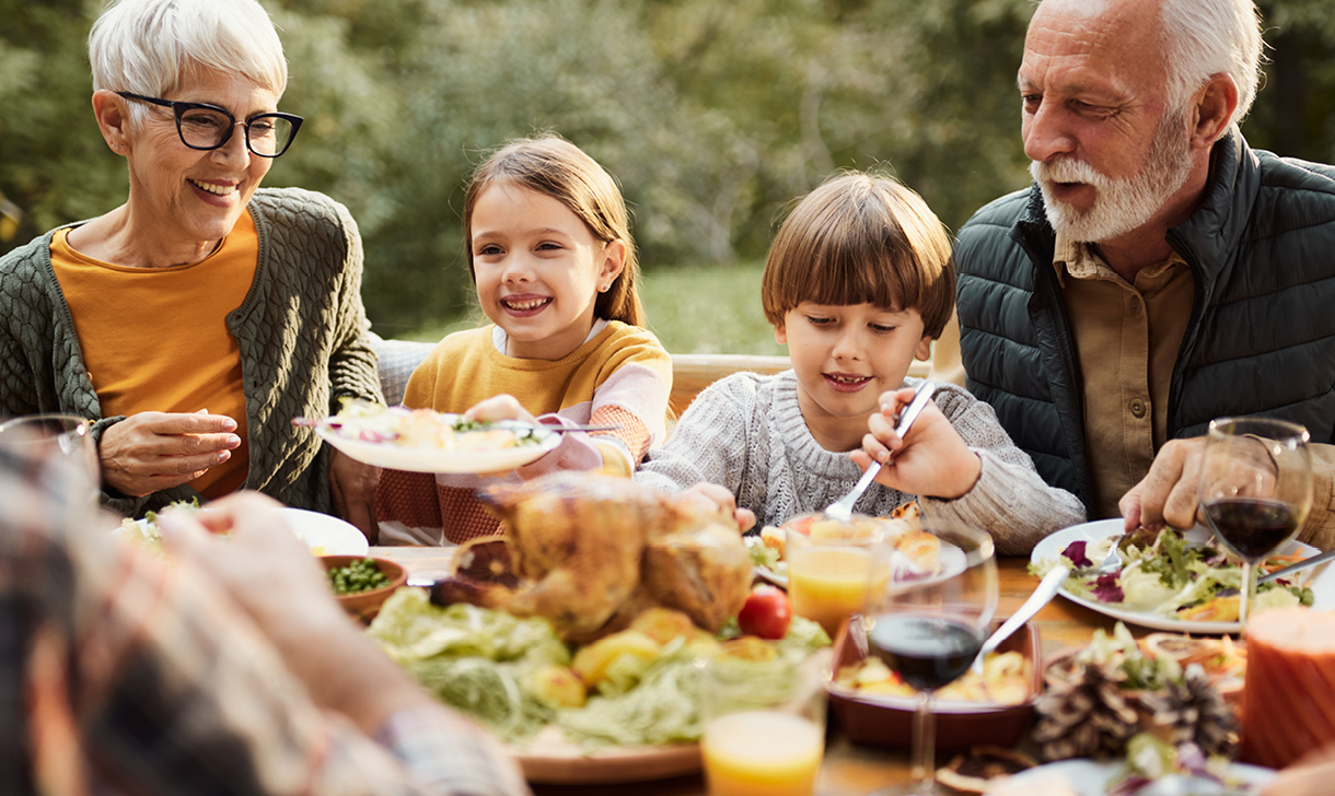 Grandparents and children enjoying a meal together outdoors.