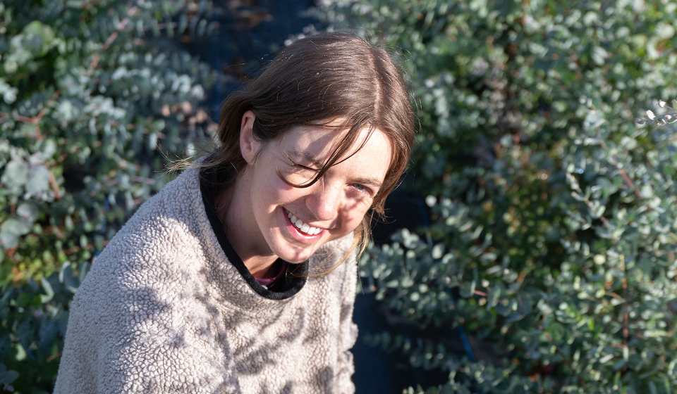Woman smiling while working in a sunny green field.