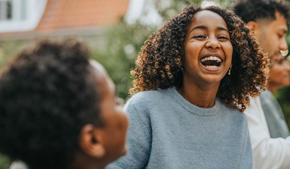 Young woman laughing outdoors with friends.