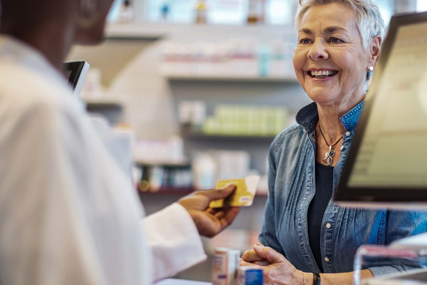 Older woman speaking with pharmacy staff at the counter