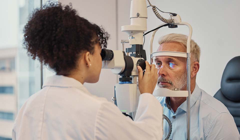Eye doctor performing a vision exam on an older adult patient.