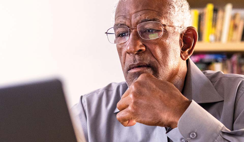 Older adult reviewing health plan information on a laptop.