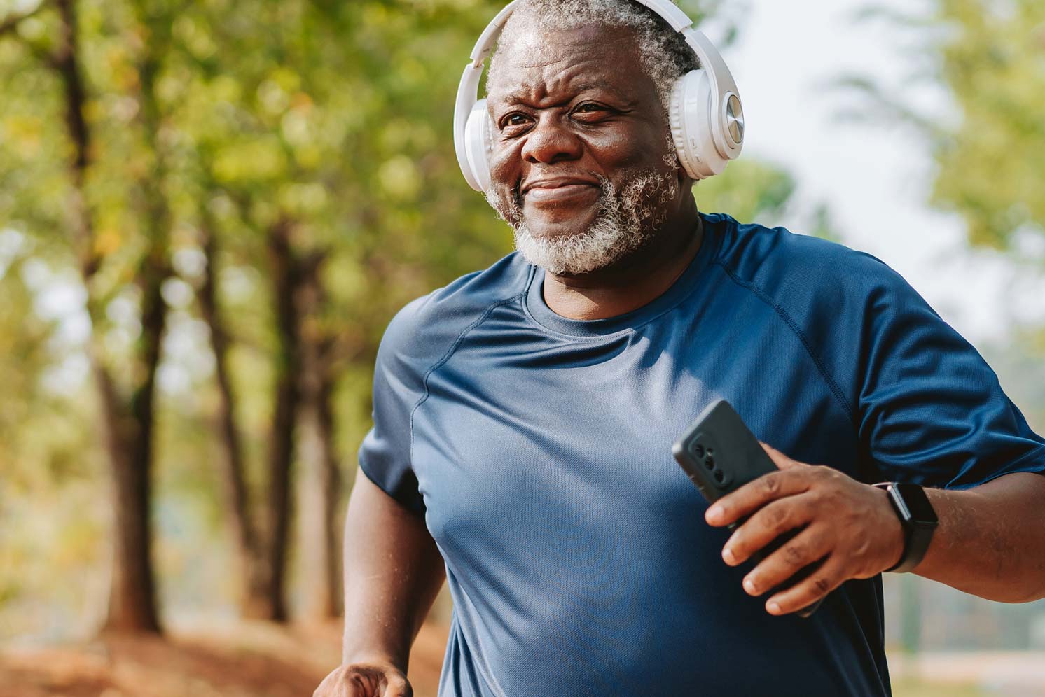 Older man wearing headphones while exercising outdoors