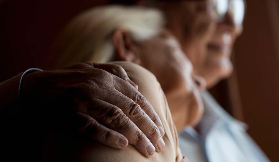 Close-up of an older couple embracing tenderly, showing warmth and support.