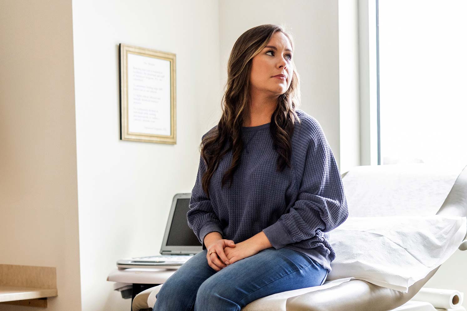 Woman sitting on an exam table waiting for a health care visit