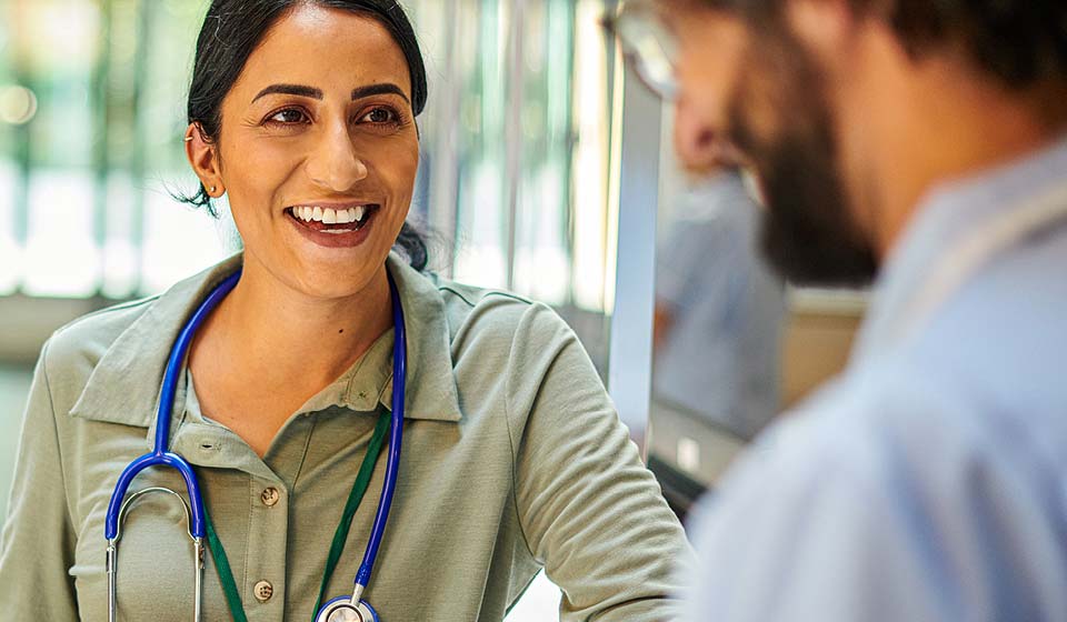 Female doctor smiling while speaking with a patient.