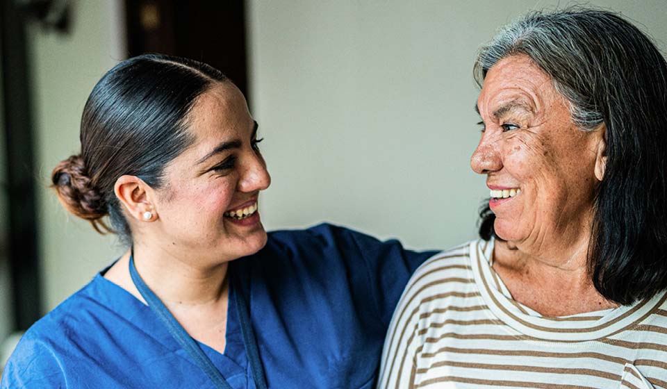 Nurse smiling while talking with an older patient.