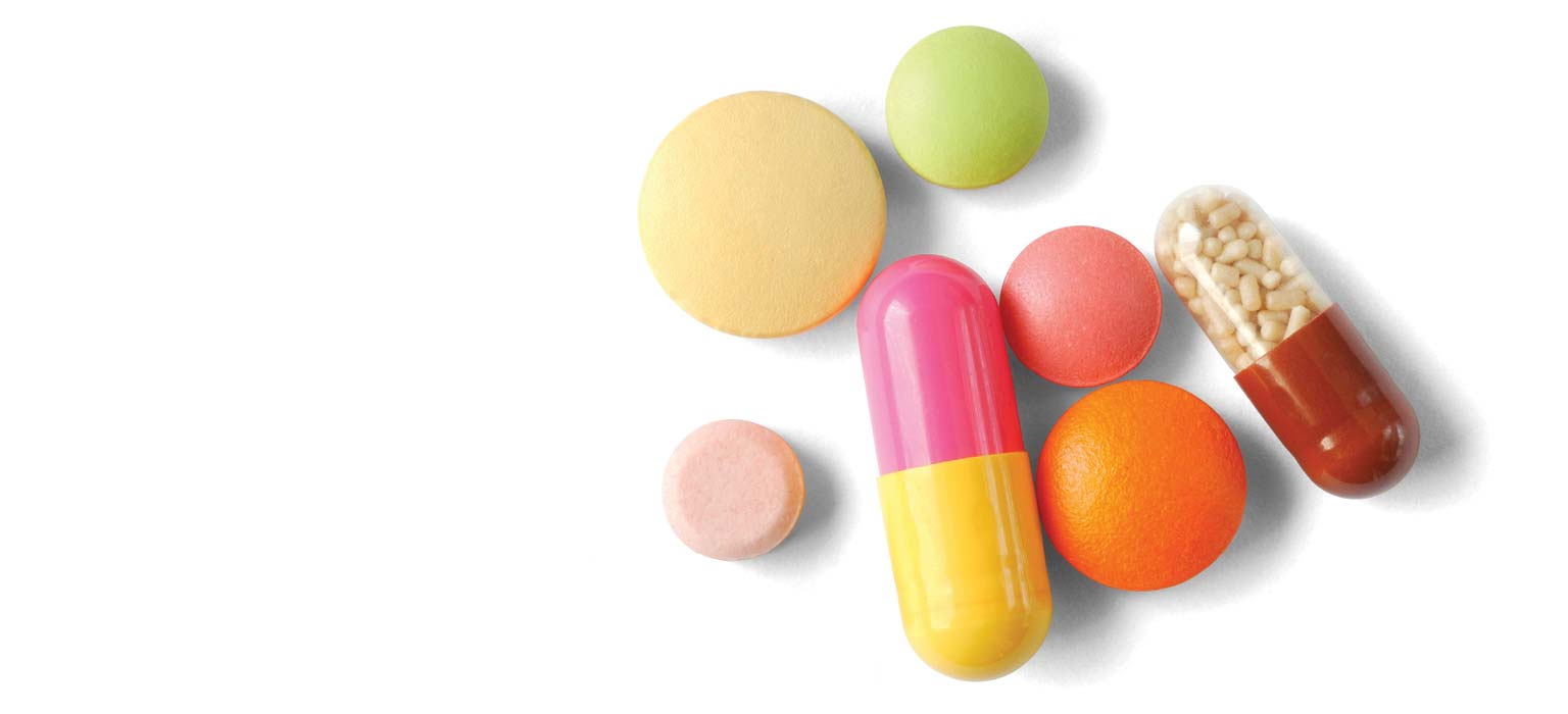 Variety of colorful pills and capsules arranged on a white background.