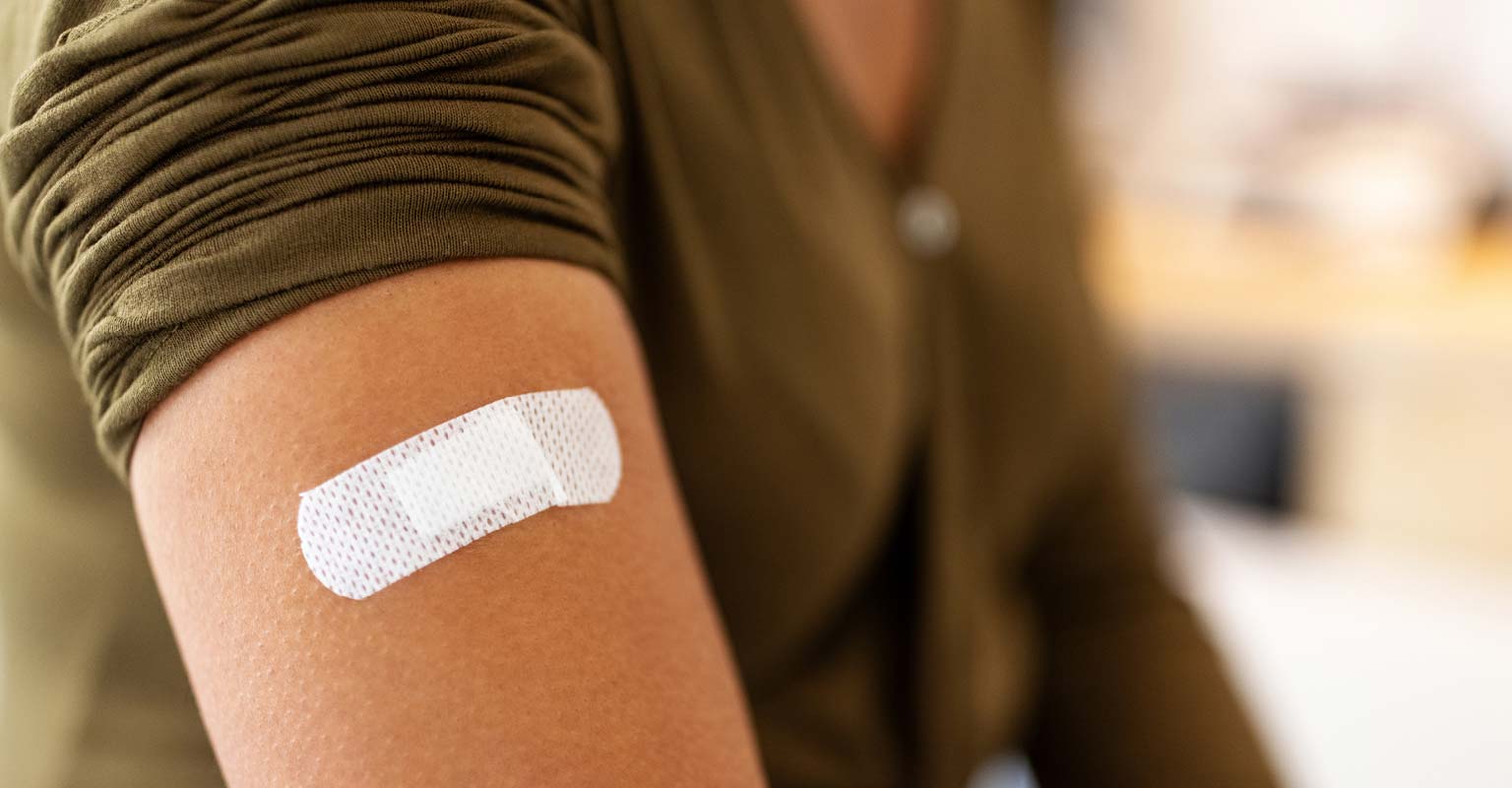 Close-up of an arm with a small bandage after vaccination.