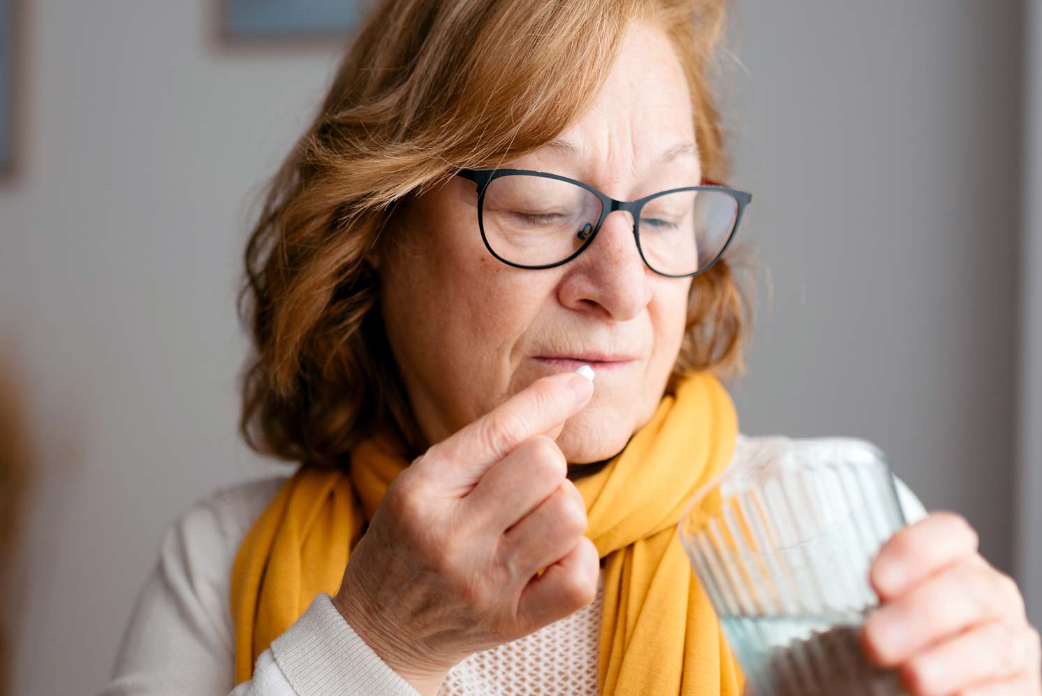 Older woman taking a pill with a glass of water