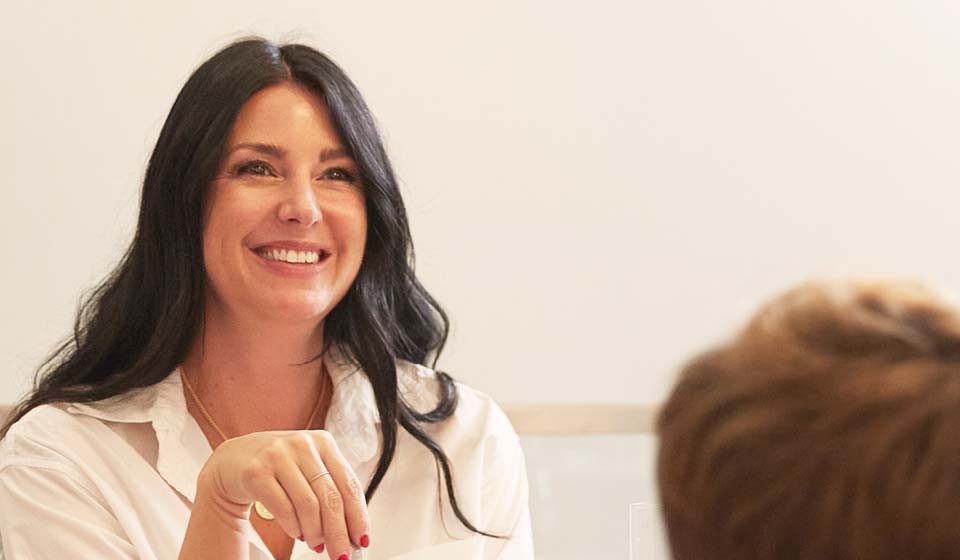 Woman smiling and engaged in a friendly conversation during a meeting.