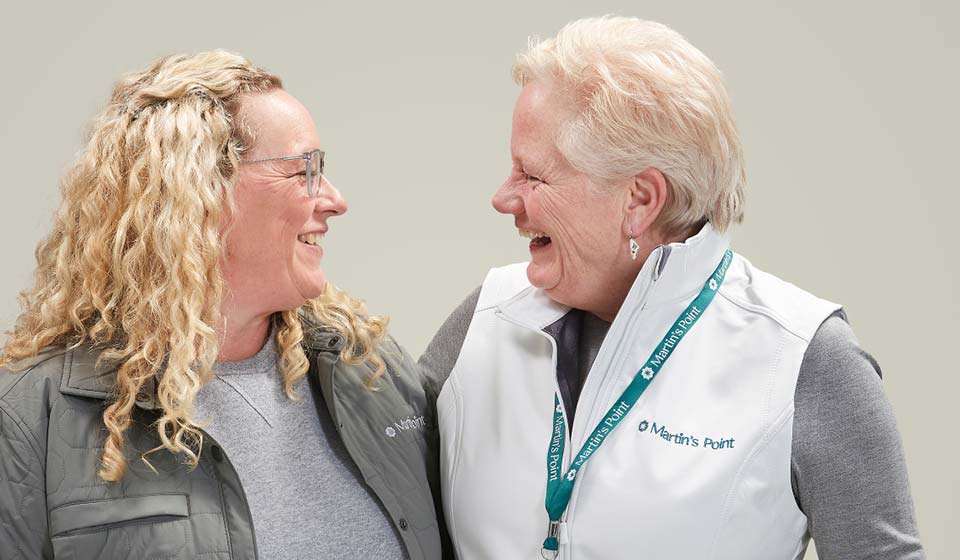 Two women wearing Martin’s Point apparel laughing together.